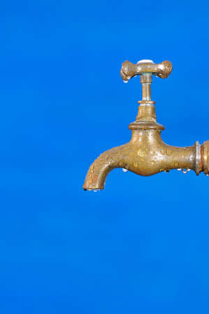 Faucet with water drops on blue backgroundの写真素材