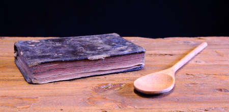 Old cookbook on wooden table with a wooden spoonの写真素材