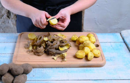 Peeling potatoes on wooden table in the kitchen.の写真素材