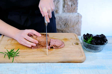 Cutting foie gras on wooden table in the kitchenの写真素材