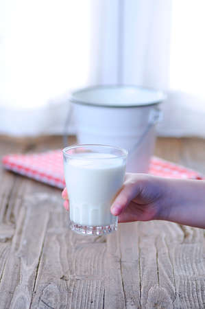 Glass of fresh milk on wooden table in the kitchen.