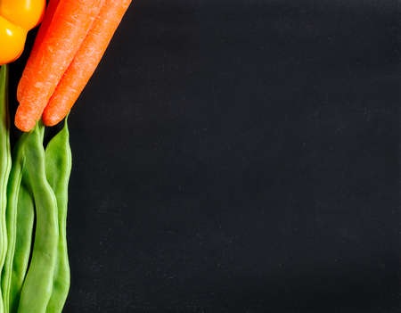 Fresh vegetables as carrots, beans and peppers on a blackboard.の写真素材