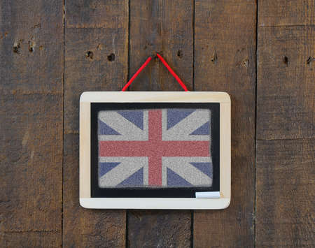 Blackboard hanging on a old wooden wall with UK flag.の写真素材