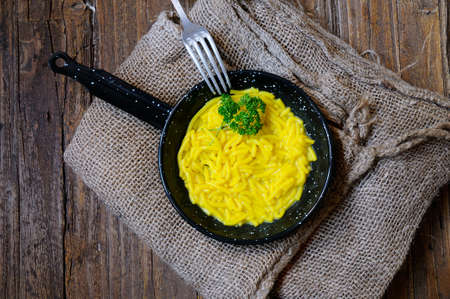 Noodles in a pan over wooden table in the kitchenの写真素材