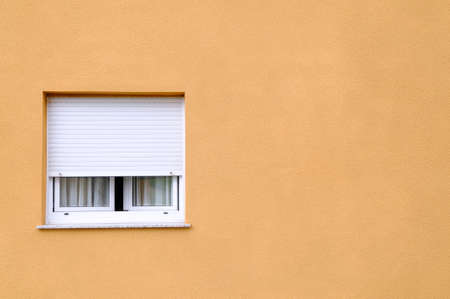A lone window in a yellow wall.の写真素材