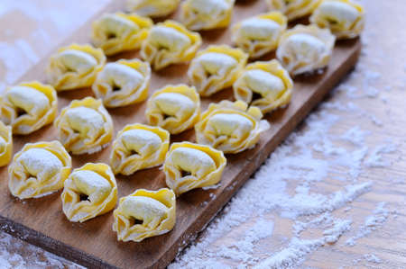 Preparing homemade tortellini on wooden table in the kitchen.の写真素材