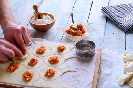 Man's hands making dumplings on wooden board. Unrecognizable