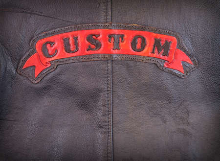 Red custom label on back of leather jacket in close-up.