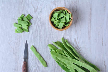 View on cut green peas with knife and bowl on wooden table. From aboveの写真素材