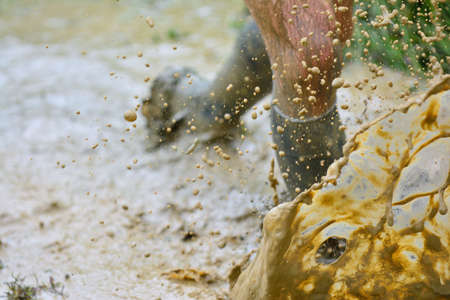 Close-up of unrecognizable man running in mud with splashes