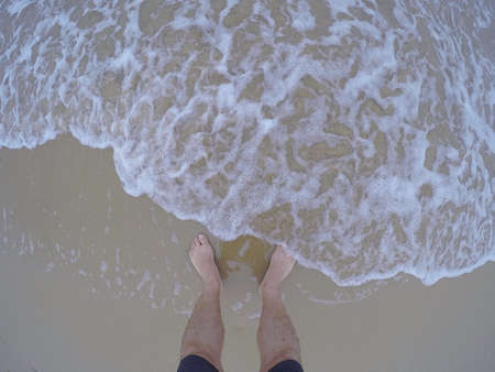 Fresh sea water touching male feet on sand.Above.Fish eye.の写真素材