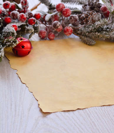 Close-up of brown wrapping paper on wooden table with snowed faux fir-tree branch with christmas ball and berriesの写真素材