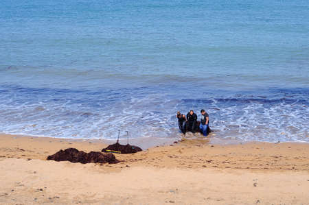 LUANCO, SPAIN - APRIL 22, 2017: People pick up seaweed on a beach in Luanco, Spain on April 22,...
