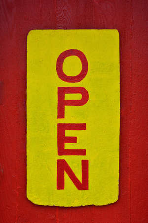 A rustic wooden "open" sign in red and yellow.の写真素材