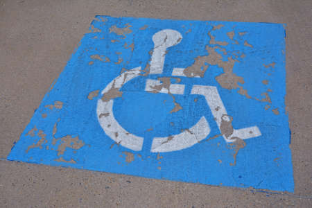 Disabled blue parking sign painted on dark asphalt.の写真素材