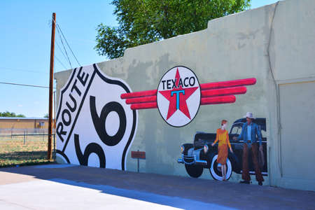 Tucumcari, New Mexico - July 21, 2017: Texaco gas station in Tucumcari,the Texaco logo, a Route 66 sign, a woman, and a cowboy on the side of a buildingのeditorial素材