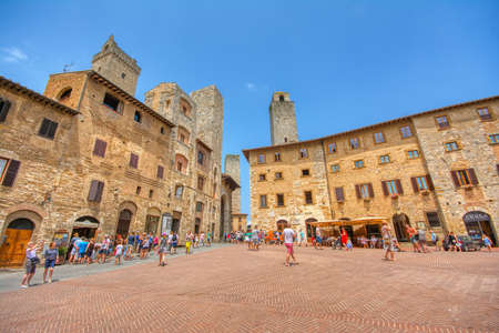 San Gimignano, Italy - July 3, 2018: Panoramic view of famous Piazza della Cisterna in the historic town of San Gimignano on a sunny day, Tuscany, Italy