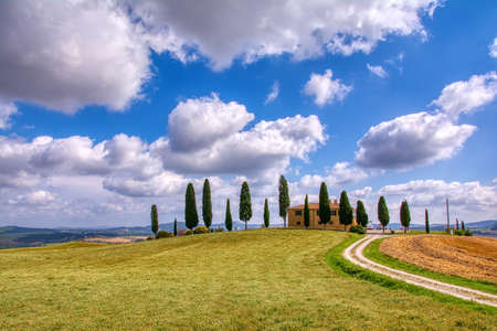 Tuscany, Italy - July 6, 2018: Cypress trees and meadow with typical tuscan house, Val d'Orcia, Italy - Tuscanyのeditorial素材