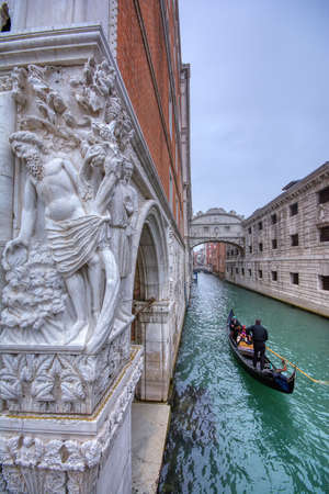 Venice, Italy - October 15, 2019: Gondola with tourists sails on old canal under medieval Bridge of Sighs, Venice, Italy. Famous historical landmark of Venice. Romantic water trip across Venice. Travel and vacation in Venice.のeditorial素材
