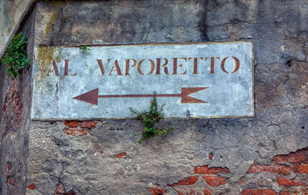 Al Vaporetto, venetian water bus. Old road sign with plants on a wall in Venice. Written in Italianの写真素材