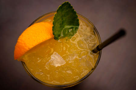 A glass with refreshing orange lemonade, a mint leaf and a straw.の写真素材