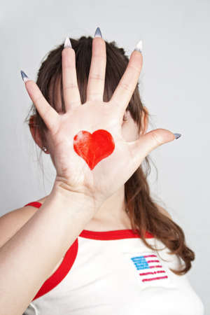The girl closed the person at hand with the heart symbol on a gray backgroundの写真素材