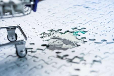 Shopping cart full of jigsaw puzzle on money dollar background, Business solution concept ,key for successの写真素材