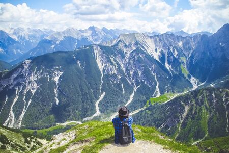 Woman traveller sitting admiring the scenery of the Alps mountains.の写真素材