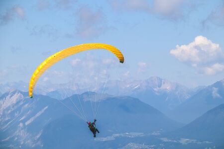 Paraglider soaring in the blue sky over the beautiful mountains.の写真素材
