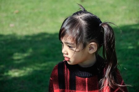 Portrait of cute Little asian girl in moment of happiness with grass background .Children wear...