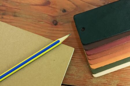 Natural leather samples variety shades of colors with notebook and pencil on wood table, designer...