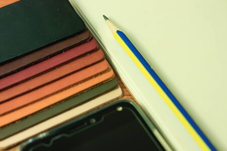 Natural leather samples variety shades of colors with notebook and pencil on wood table, designer...