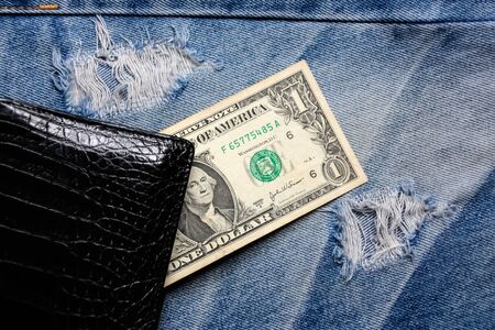 Black leather wallet with money on back blue jeans pocket denim background texture.の写真素材