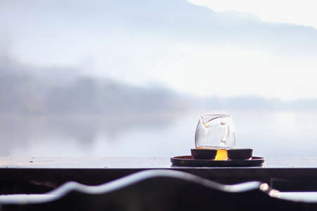 Morning cup of hot tea with lake background at sunrise.の写真素材