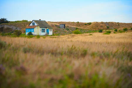 Old single russian house on a meadow in the end of summerの写真素材