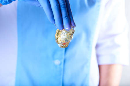 New clear golden sugaring paste in the hand in a blue latex glove