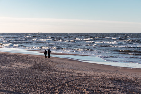 Two people walking on a sandy beach by the Baltic Sea in winterの写真素材
