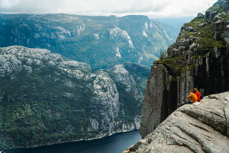 Tourism vacation and travel. People sitting on the edge of a cliff and enjoying the view over the...