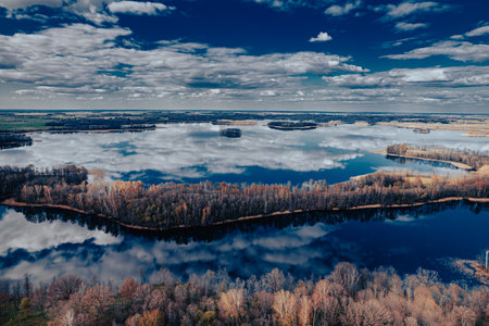 Aerial view of the autumn forest and lake with reflection in water