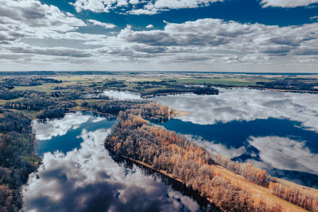 Aerial view of autumn forest lake with reflection of clouds in waterの写真素材