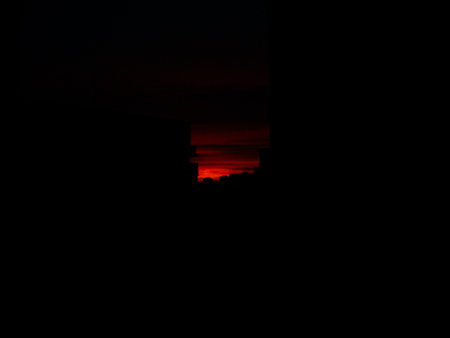 Sunset in the dark sky with a silhouette of a building.の写真素材