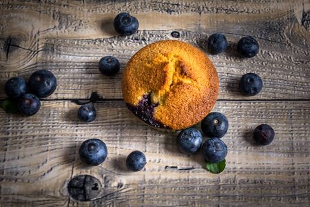 Blueberry muffins with blueberries on wooden spoons and wooden backgroundの写真素材