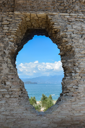 A hole in the wall of the Grotto di Catullo is like a portal with a view of Lake Gardaのeditorial素材