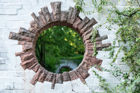 A round hole in a brick wall in a park looks like a portal to another dimensionの写真素材