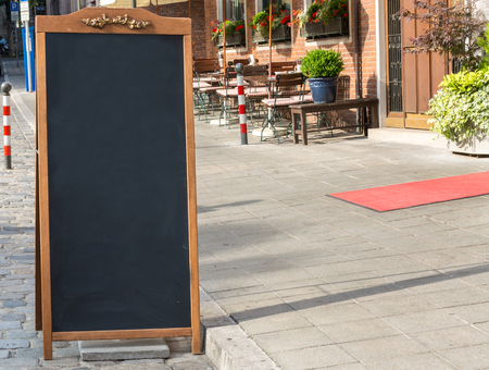 A black chalkboard stand on wood for a restaurant menu in the streetの写真素材