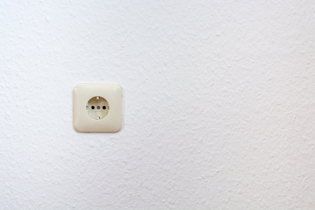 One single european plug on a white wall from the front