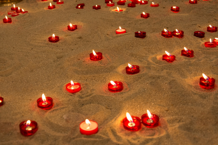 Lots of lit candles on sand in a church to pray for people who diedの写真素材