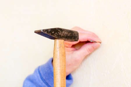 Hammer a nail into a wall as a close upの写真素材