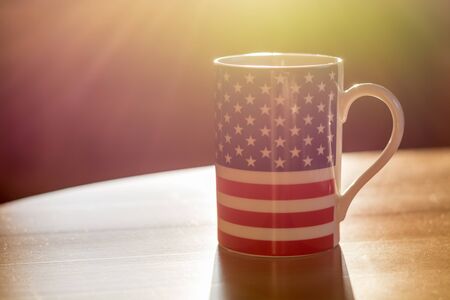 A flag of the United States of America on a mug close up with sun rays and blurry backgroundの写真素材