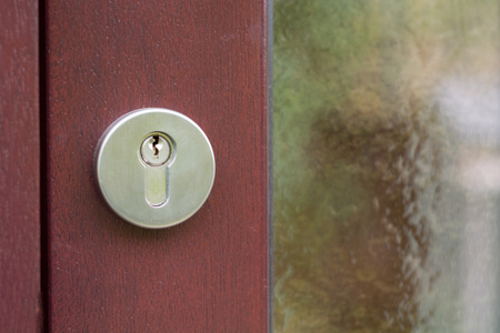 A metal keyhole on brown wooden door close upの写真素材